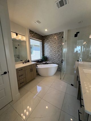 Model Home A luxurious bathroom featuring a freestanding soaking tub, black and white accent wall, and a frameless glass shower in Esperanza by Scott Felder Homes (Boerne, TX).