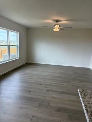An airy living space with wood flooring, a ceiling fan, and abundant natural light.