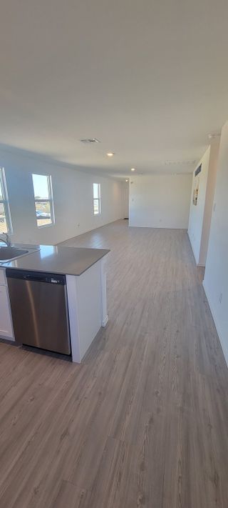 Model Home An open-concept living space with sleek flooring, a modern kitchen island, and ample natural light from multiple windows.