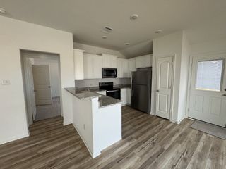 Model Home A modern kitchen featuring sleek white cabinets, stainless steel appliances, and wood-look flooring.