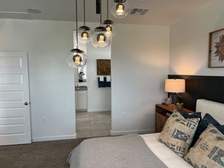A cozy bedroom with modern pendant lights and a neutral palette, featuring patterned cushions and a warm bedside lamp.