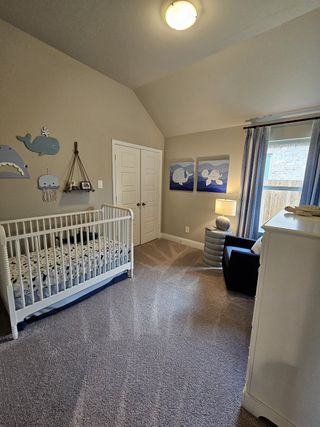 Model Home A cozy nursery featuring a white crib, ocean-themed decor, plush carpet, and soft lighting, creating a serene ambiance.