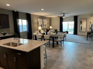 An open-concept living area featuring a granite kitchen island, sleek dining set, and cozy seating with natural light.