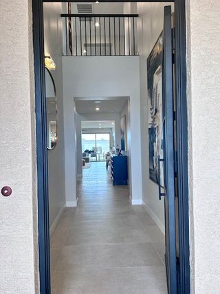 A welcoming entryway with tiled flooring, elegant artwork, and a view leading to an open, light-filled living area.