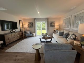 A cozy living room with a plush beige sofa, modern accents, and a large window overlooking greenery.