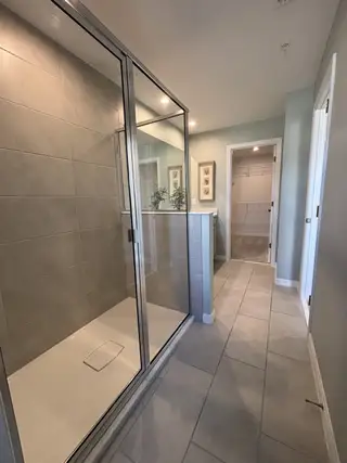 A modern bathroom with a sleek glass shower, large tiles, and soft lighting for a refreshing ambiance.