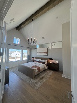 A modern bedroom with vaulted ceilings, wood beams, large windows, and a cozy bed, offering a serene retreat.