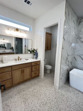 Model Home A chic bathroom with a wood vanity, marble shower, and elegant lighting.