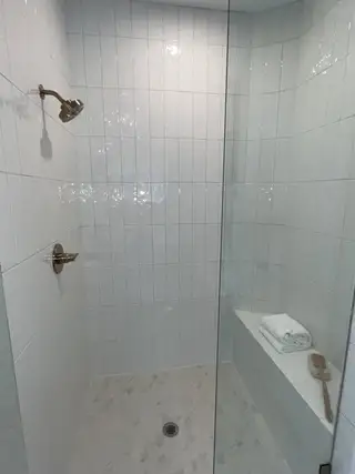 Model Home A sleek, tiled shower with a glass door, built-in bench, and modern fixtures.