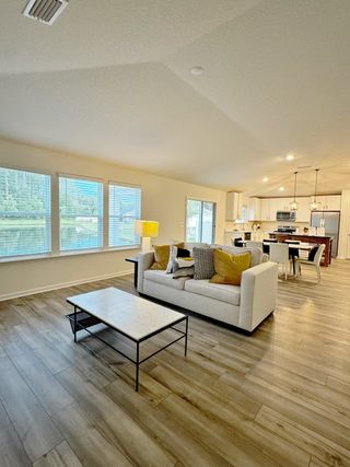 A bright, open living space with a cozy sofa, modern coffee table, and a seamless flow to the dining area and kitchen.