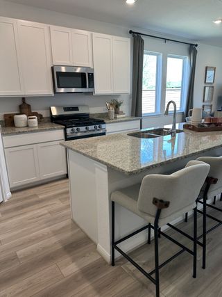 Model Home A modern kitchen featuring white cabinets, granite countertops, and a cozy island with seating.