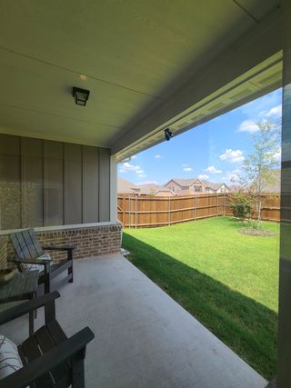 Model Home A cozy covered patio overlooking a lush green lawn, perfect for relaxation.