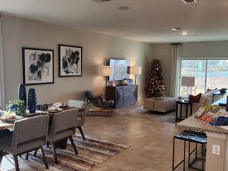 A cozy open-plan living area with stylish decor, festive Christmas tree, abstract art, and ample natural light streaming from large windows.