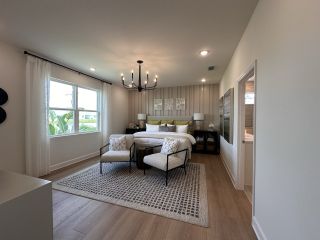 A spacious bedroom with a cozy bed, elegant chandelier, and large window offering natural light.