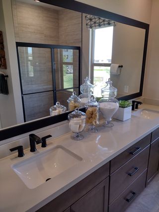 A modern bathroom with a large mirror, sleek black fixtures, and elegant countertop displays adding sophistication.