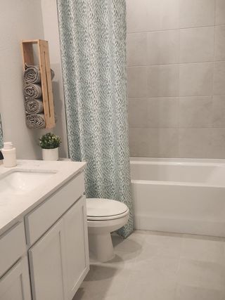 A modern bathroom featuring a sleek vanity, elegant shower curtain, and neutral tile flooring for a clean, sophisticated look.