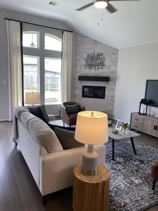 A cozy living room with a sleek fireplace, large window, and modern decor.