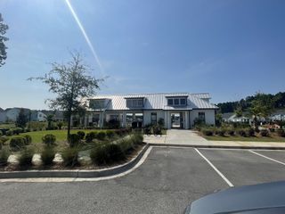 Charming clubhouse with a modern metal roof and landscaped grounds in Homecoming by True Homes (Ravenel, SC).