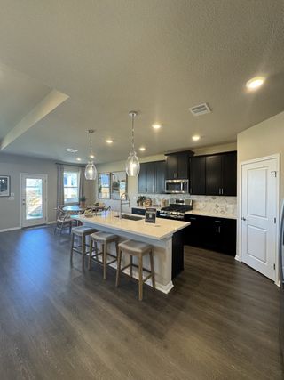 A gourmet kitchen with dark cabinetry, pendant lighting, and a large center island, seamlessly connecting to the living space.