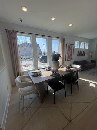 A chic dining area with a modern wooden table, elegant seating, and large windows in Solterra Texas by Cadence Homes (Mesquite, TX).