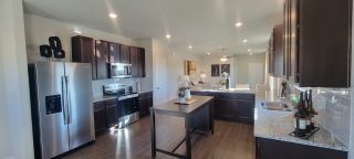 A modern kitchen with dark wood cabinets, stainless steel appliances, and a spacious island countertop.