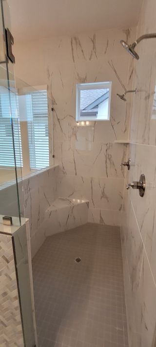 Model Home A spacious shower with marble-patterned tiles, glass door, and modern fixtures. Perfect for a luxury bathroom retreat.