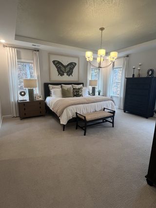 A cozy bedroom featuring a stylish chandelier, elegant decor, and a comfortable bed with soft, neutral tones.