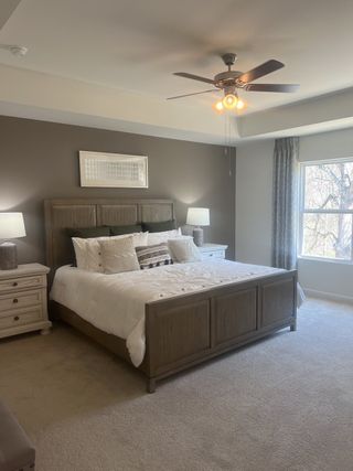 A serene bedroom with a cozy bed, soft lighting, elegant decor, and a large window with leafy views.