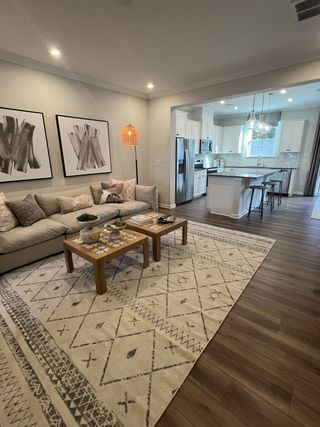 Model Home An inviting open-plan living area with cozy seating, chic artwork, and a modern kitchen with a spacious island.