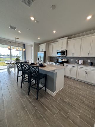 A modern kitchen with sleek cabinetry, stainless steel appliances, and a spacious island overlooking a bright dining area.
