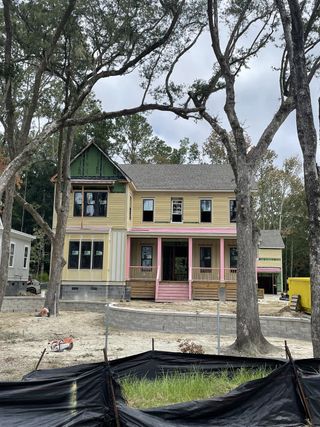 A charming yellow and pink home under construction in Riverside at Carolina Park by Homes by Dickerson (Mount Pleasant, SC).