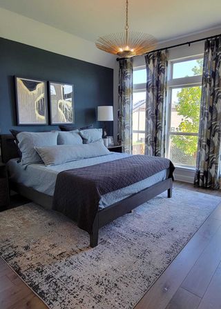 Sophisticated bedroom with a dark accent wall, modern art, and elegant lighting, featuring large windows and lush drapes.