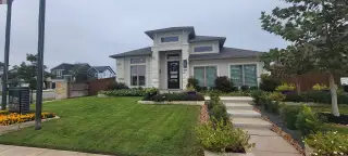 A modern stone home with lush landscaping in Stillwater Ranch 40' by Perry Homes, San Antonio, TX.
