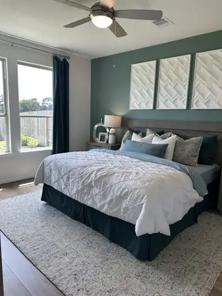A serene bedroom featuring a cozy bed with textured bedding, modern decor, and large windows for natural light.