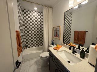 A modern bathroom with black and white checkered tiles, a sleek vanity, and chic lighting.