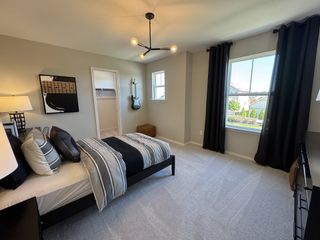 A cozy bedroom with modern decor, gray walls, elegant lighting, and a large window with dark curtains.
