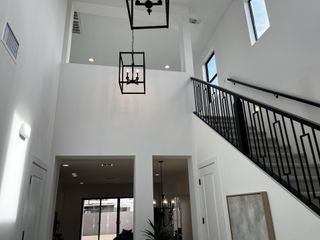 Model Home A modern foyer with sleek black railings, high ceilings, and elegant pendant lighting.