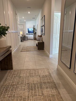 A modern hallway with sleek tile floors, cozy seating, and stylish decor leading to a bright living area.