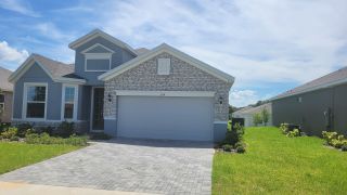 Street view A charming home with a stone facade and manicured lawn in Seaport Village by Dream Finders Homes (Tavares, FL).