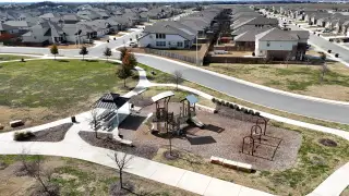 Community Amenities Scenic park view in August Fields by Chesmar Homes, New Braunfels, TX, featuring a playground and lush green space.