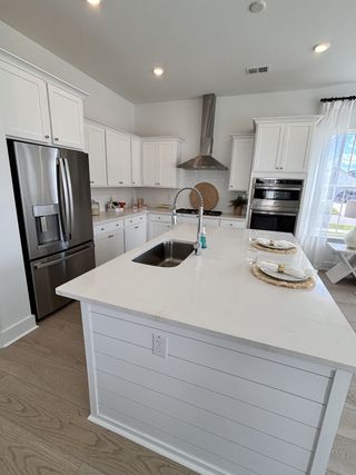 A modern kitchen with white cabinetry, sleek stainless steel appliances, and a central island offering ample space and style.