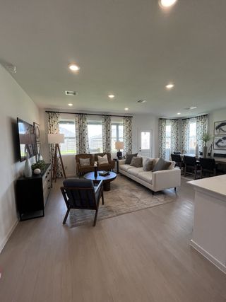 A bright living room boasts sleek furnishings, patterned curtains, and abundant natural light for a cozy, modern atmosphere.