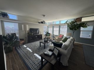 Model Home A cozy living room with large windows, elegant furnishings, and abundant natural light, featuring a stylish rug and lush plants.