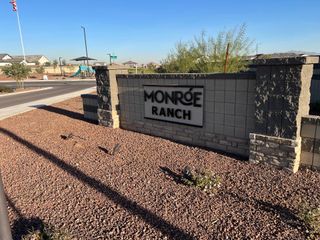 Entrance to Monroe Ranch by K. Hovnanian® Homes, featuring a modern stone sign and landscaped surroundings in Buckeye, AZ.