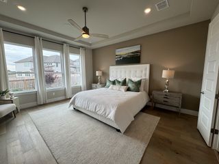 A spacious bedroom with large windows, a plush bed, elegant lamps, and modern decor.