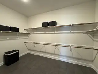 A spacious walk-in closet featuring tiled flooring, multiple shelves, and storage baskets for an organized living space.