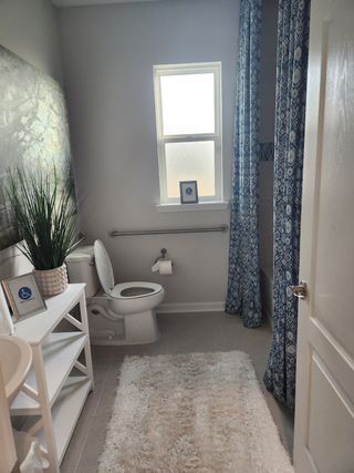A cozy bathroom with patterned blue curtains, a soft rug, and a chic white shelving unit.