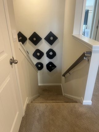 A cozy carpeted stairway with modern black geometric wall art and sleek wooden handrails.