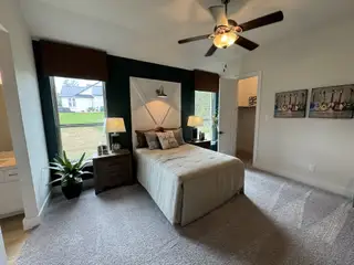 Model Home A cozy bedroom with a feature wall, large windows, and warm lighting.