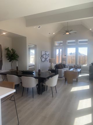 A modern living-dining area with high ceilings, light wood floors, and large windows for abundant natural light.